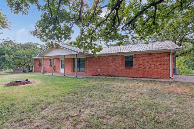 back of house featuring a lawn and an outdoor fire pit