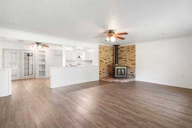 unfurnished living room featuring french doors, a wood stove, and dark wood-type flooring