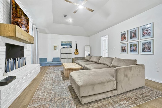 living room with hardwood / wood-style flooring, ceiling fan, a tray ceiling, and vaulted ceiling