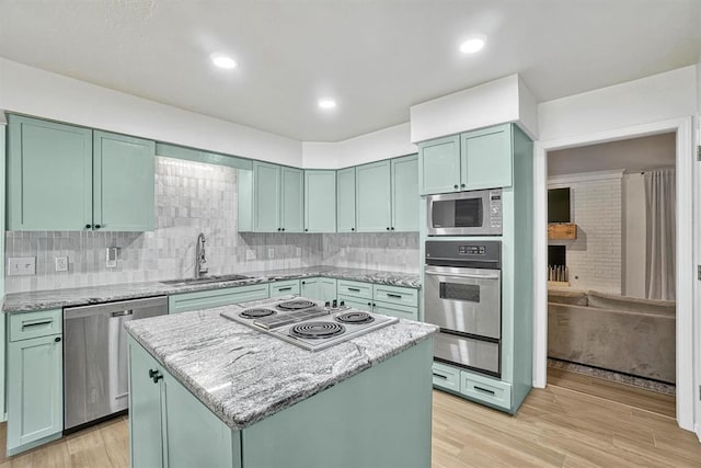 kitchen with sink, a center island, stainless steel appliances, green cabinets, and light hardwood / wood-style flooring