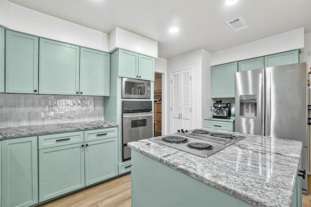 kitchen featuring appliances with stainless steel finishes, light hardwood / wood-style floors, light stone counters, and green cabinetry