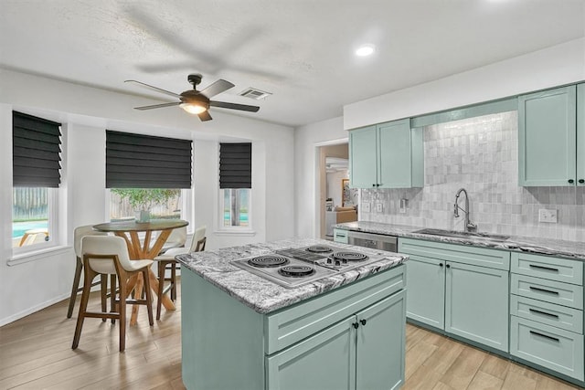 kitchen with green cabinets, light hardwood / wood-style flooring, stainless steel appliances, and sink