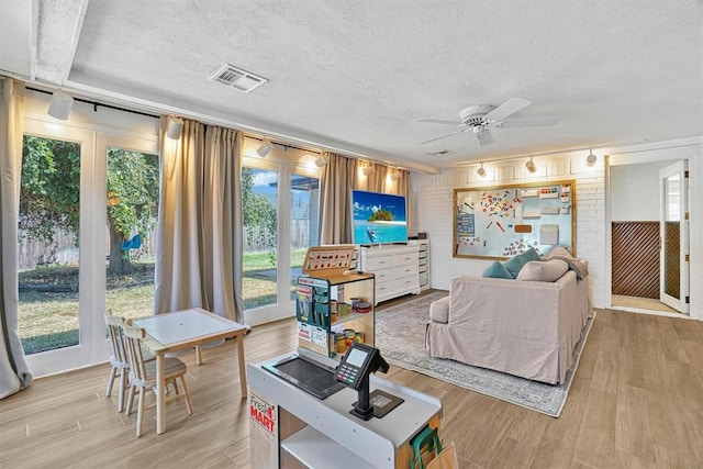 living room featuring a textured ceiling, light hardwood / wood-style flooring, and ceiling fan