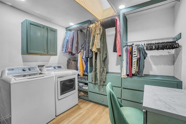 washroom featuring washer and dryer, light wood-type flooring, and cabinets