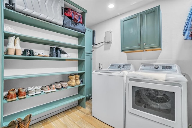 washroom featuring washing machine and dryer, light hardwood / wood-style flooring, and cabinets