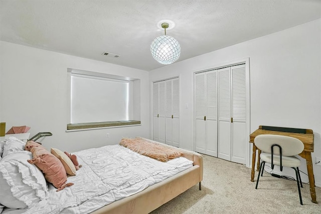 carpeted bedroom with a textured ceiling and two closets