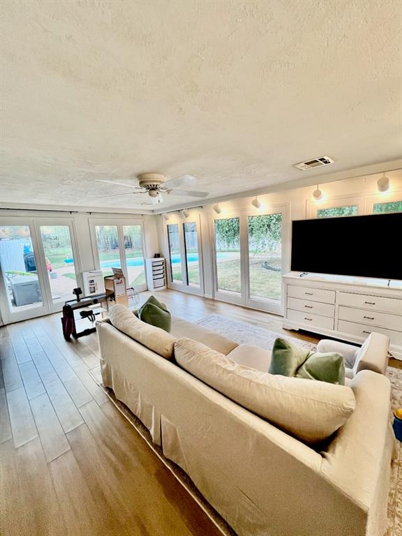 living room featuring french doors, a textured ceiling, light hardwood / wood-style flooring, and plenty of natural light