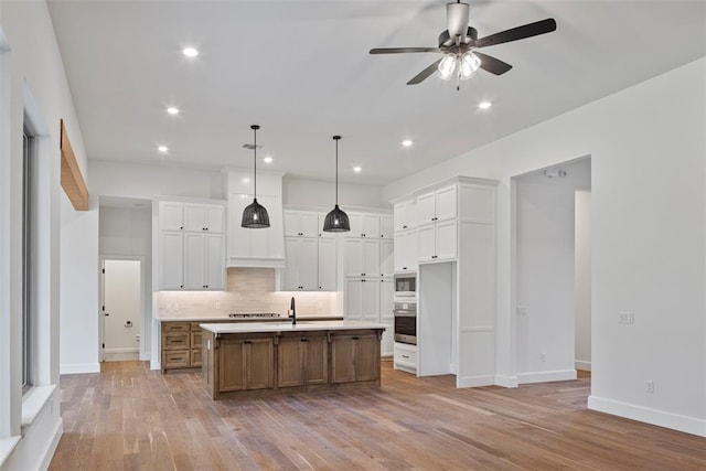 kitchen featuring pendant lighting, a large island, light wood-type flooring, and white cabinetry