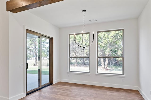 unfurnished dining area featuring light hardwood / wood-style floors, beam ceiling, and an inviting chandelier