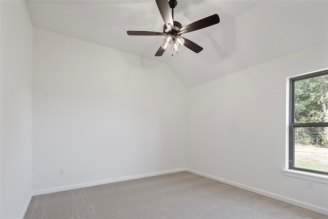 carpeted empty room with a wealth of natural light, ceiling fan, and vaulted ceiling