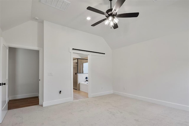 unfurnished bedroom with ceiling fan, lofted ceiling, light carpet, and ensuite bath