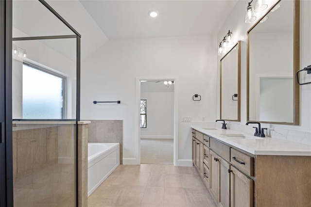 bathroom featuring tile patterned flooring, plenty of natural light, a bath, and vaulted ceiling