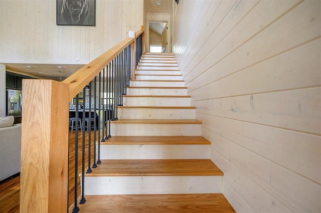 stairs with hardwood / wood-style floors and wooden walls