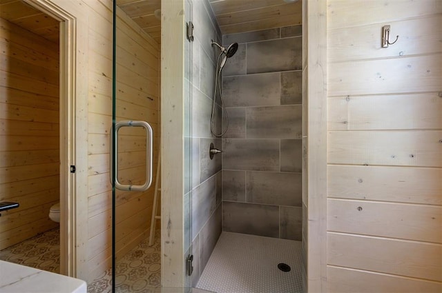 bathroom featuring wooden walls, a shower with shower door, and toilet