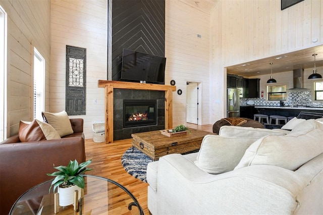 living room with a tile fireplace, a wealth of natural light, a high ceiling, and hardwood / wood-style flooring