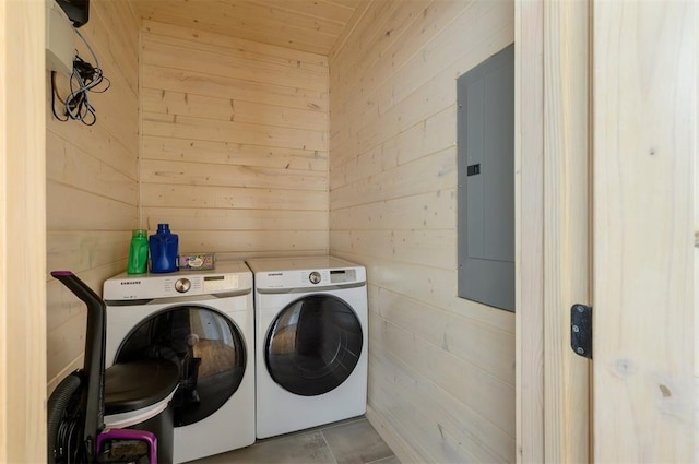 washroom featuring electric panel, washer and clothes dryer, and wooden walls