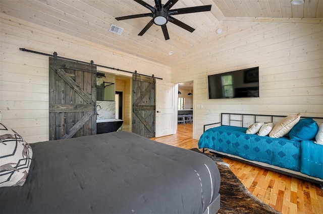 bedroom with a barn door, ceiling fan, vaulted ceiling, and hardwood / wood-style flooring