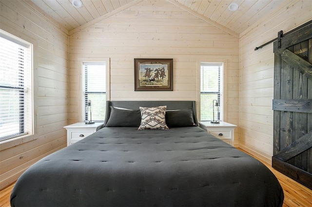 bedroom with a barn door, multiple windows, and lofted ceiling