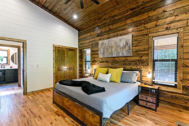 bedroom featuring wood walls, ensuite bathroom, ceiling fan, light wood-type flooring, and wood ceiling