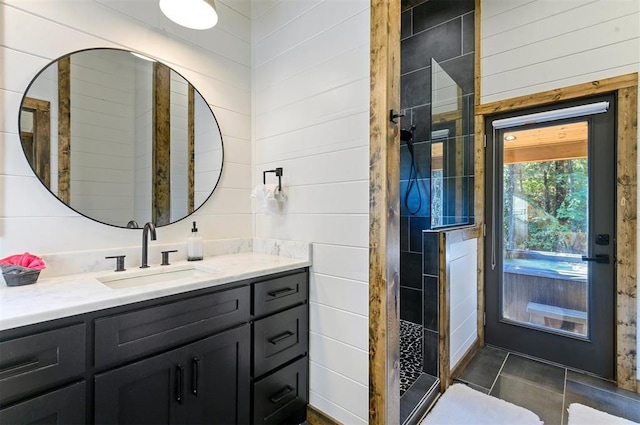 bathroom with tile patterned flooring, vanity, walk in shower, and wooden walls