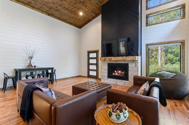 living room with a stone fireplace, wooden ceiling, high vaulted ceiling, and light hardwood / wood-style flooring