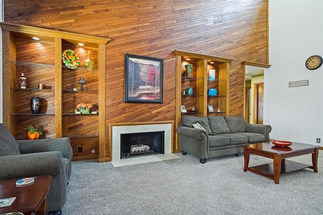 carpeted living room featuring wooden walls and a high ceiling