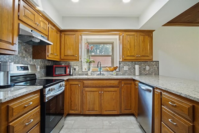 kitchen featuring light stone countertops, appliances with stainless steel finishes, tasteful backsplash, and sink