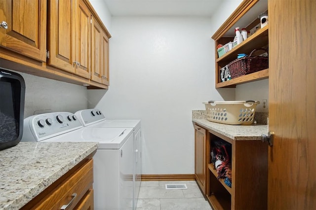 laundry area featuring light tile patterned flooring, cabinets, and washing machine and clothes dryer