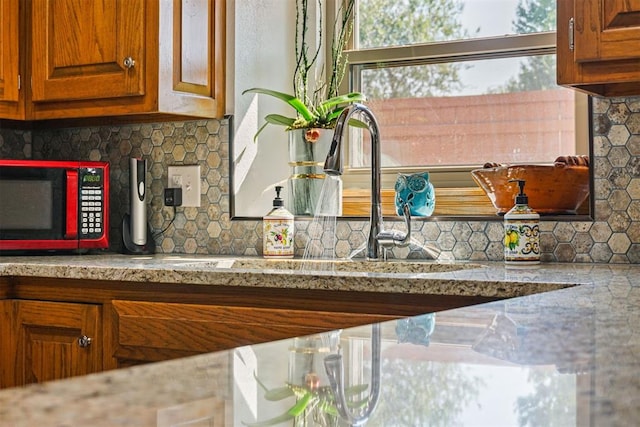 interior details with backsplash, light stone counters, and sink