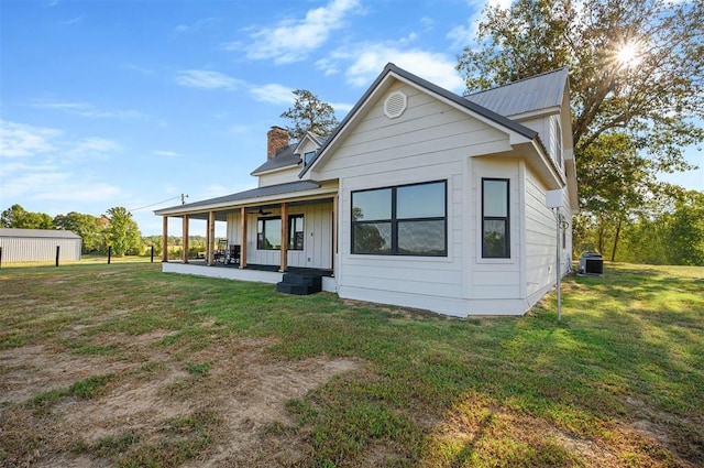 back of property with covered porch, a yard, and central AC