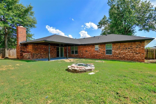 back of house featuring a fire pit, a patio area, and a lawn