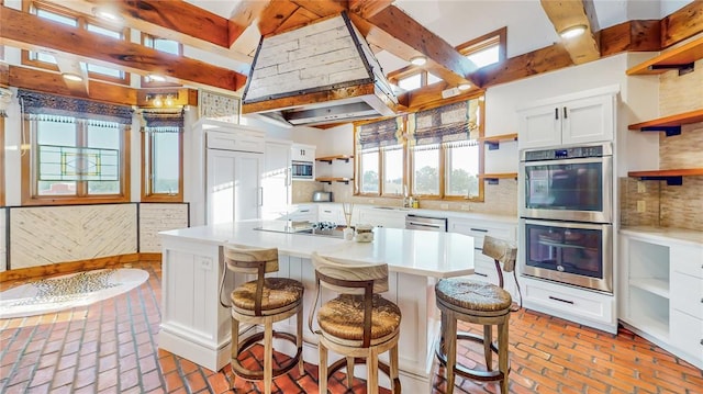 kitchen featuring white cabinets, backsplash, custom range hood, and stainless steel appliances