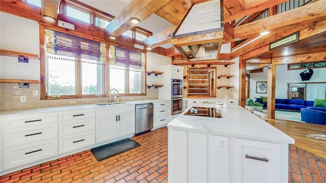 kitchen with white cabinetry, sink, tasteful backsplash, a kitchen island, and appliances with stainless steel finishes