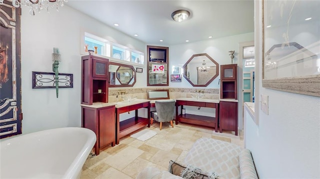 bathroom with a washtub, vanity, and a notable chandelier