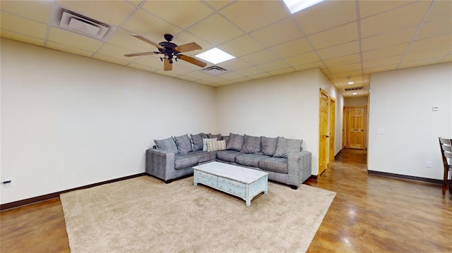 living room featuring a paneled ceiling, ceiling fan, and concrete floors