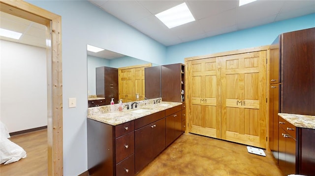 bathroom with a paneled ceiling, vanity, and concrete floors