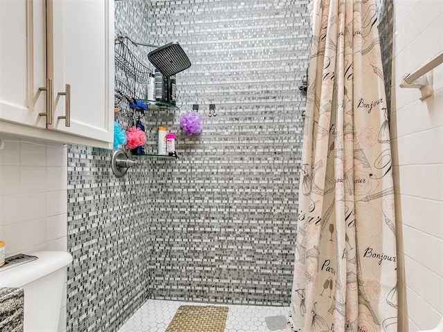 bathroom featuring curtained shower, toilet, and tile walls