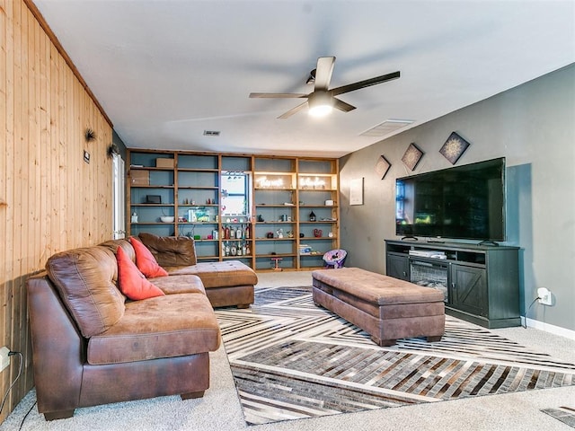 carpeted living room featuring wooden walls and ceiling fan