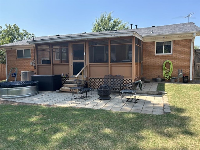 rear view of property featuring a yard, a sunroom, a fire pit, and a patio