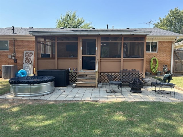 back of house with an outdoor fire pit, a lawn, a patio area, a sunroom, and central air condition unit