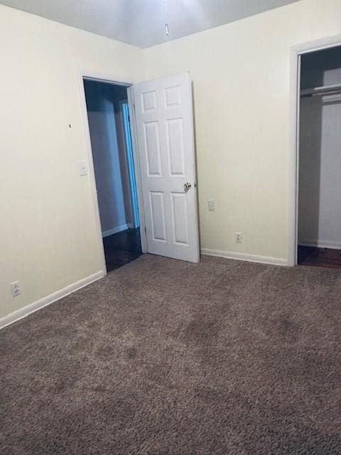 unfurnished bedroom featuring a closet and dark colored carpet