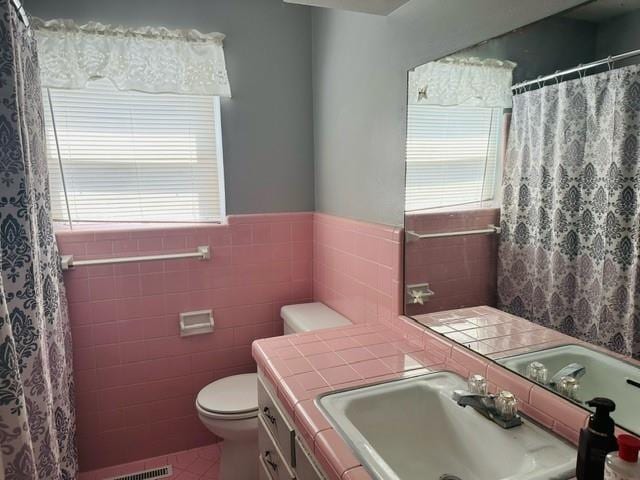 bathroom with toilet, tile walls, tile patterned floors, and vanity