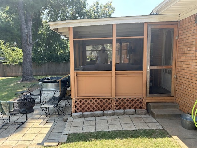 view of patio / terrace featuring an outdoor fire pit and a sunroom