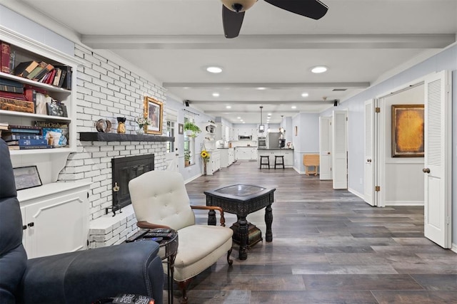 living room with a fireplace, beamed ceiling, ceiling fan, and dark wood-type flooring