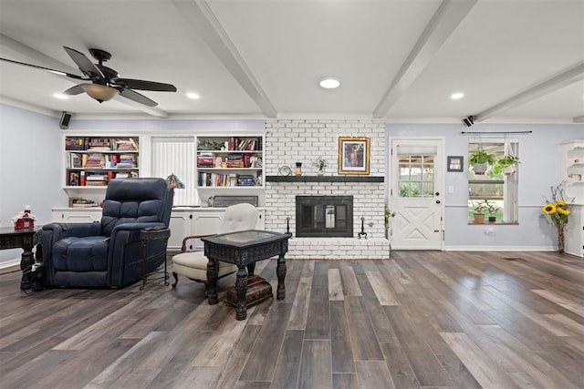 living room featuring beamed ceiling, ceiling fan, wood-type flooring, and a fireplace