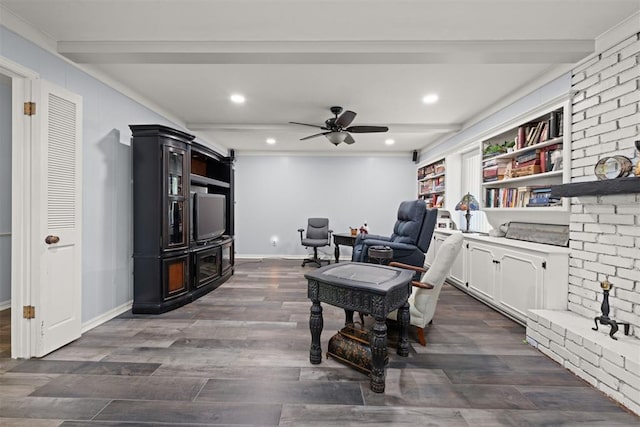 living area featuring beamed ceiling, ornamental molding, ceiling fan, and dark wood-type flooring