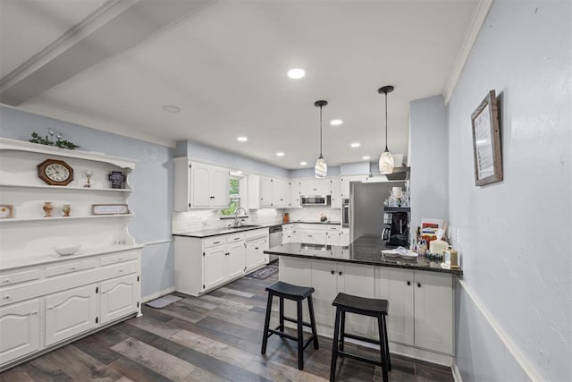 kitchen featuring white cabinets, appliances with stainless steel finishes, a kitchen bar, and sink