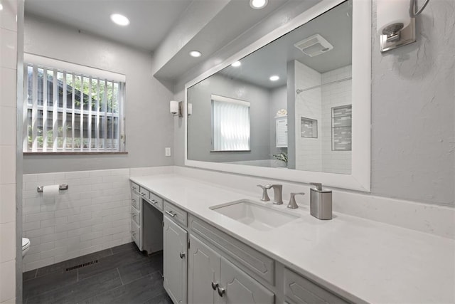 bathroom with vanity, tile walls, and toilet