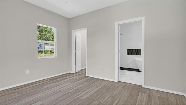 unfurnished bedroom featuring light hardwood / wood-style floors and ensuite bath