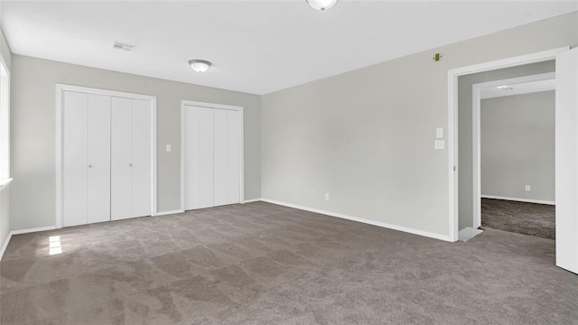 unfurnished bedroom featuring carpet and two closets